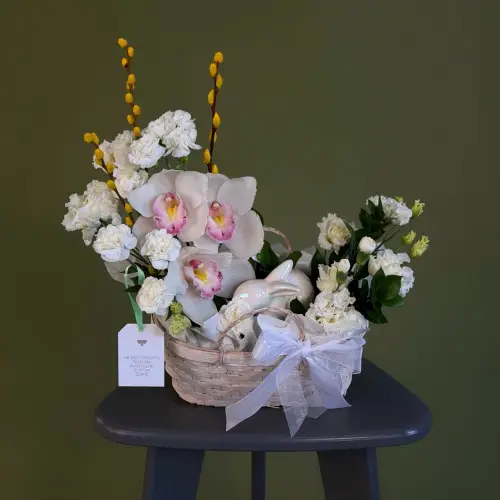 Цветочная композиция из гвоздик, орхидей и вербы с эустомой в плетеной корзине